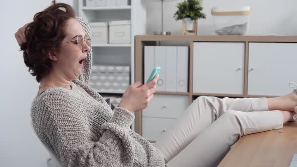 Young Woman Procrastinates Scrolling her Smartphone