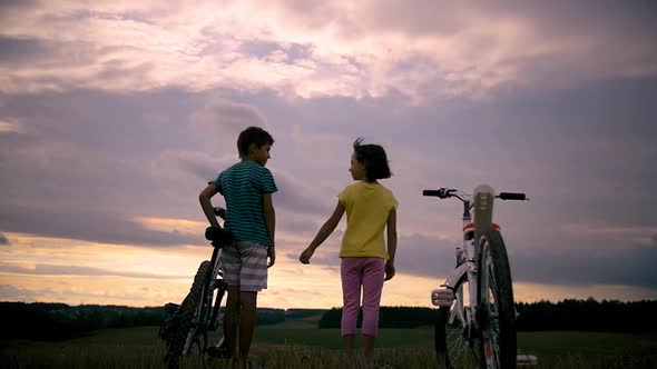 Boy with Girl with Bicycles in the Field Holding Hands at Sunset Strong Wind on a Hill Cinematic