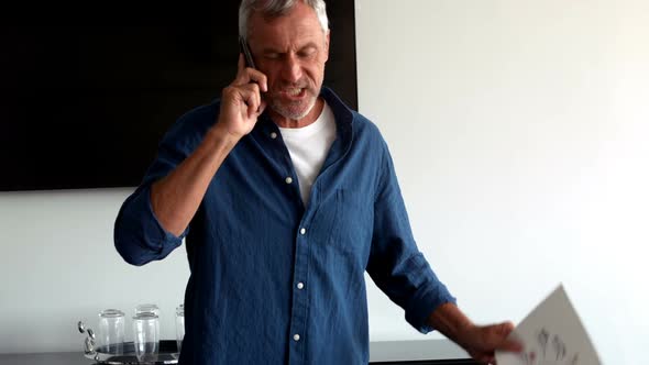 Frustrated male executive talking on mobile phone alt