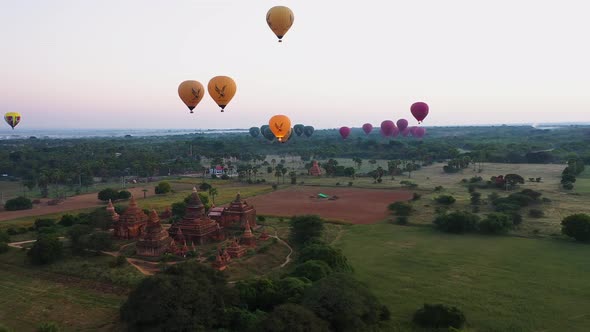 Sideway aerial shot of the hot air balloons floating over the temple in Bagan Myanmar alt