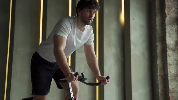 Young Fitness Man Exercising His Legs Cardio Training on Bicycle in Gym alt