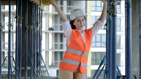 Female architect having fun dancing at construction siteof an under-construction building alt