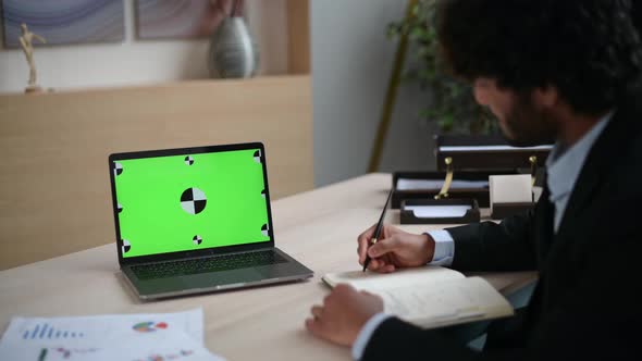 Over the Guy's Shoulder View of a Laptop with a Chromatic Green Screen alt