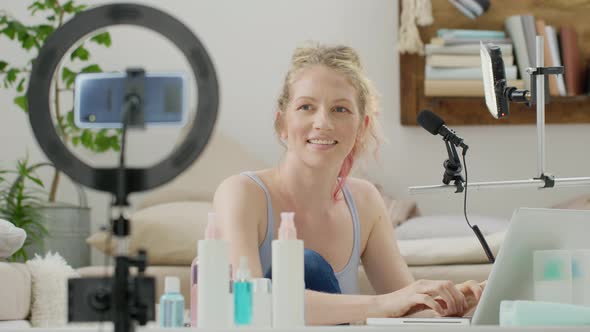 Blonde smiling woman influencer blogger recording a video tutorial on smartphone camera