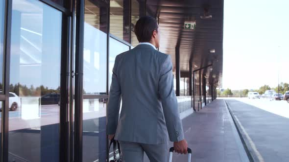 Elegant businessman walking with suitcase along the airport. Young mail entrepreneur. alt