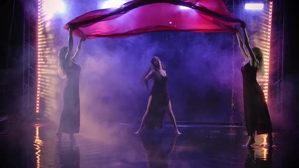 The Dance Group of Women Gracefully Dance with a Silk Red Cloth Among the Raindrops. Filmed in a alt