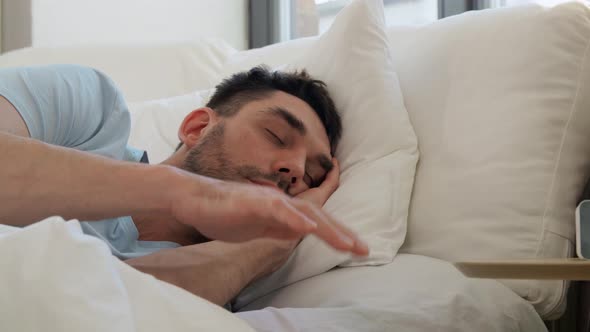 Sleeping Man Delaying Alarm Clock in Morning