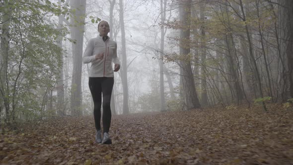 Woman Jogging on Foggy Day in Autumn Forest Front View