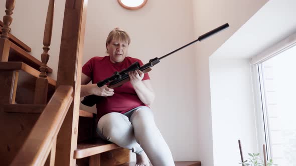 Self defense concept. Middle aged woman holding a riffle. alt