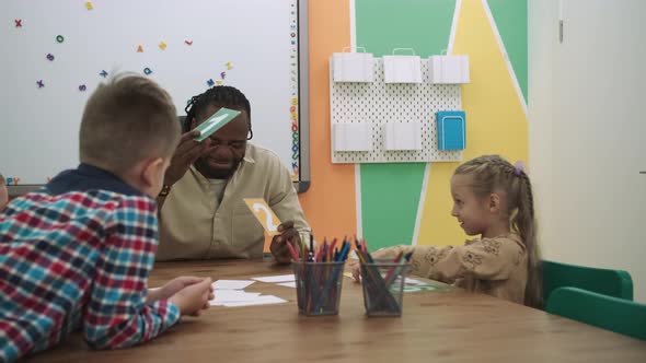 African American Teacher and a Group of Children are Learning Numbers While Sitting at the Table in alt