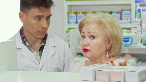 Senior Woman Asking Pharmacist for Advice, Shopping at Drugstore alt