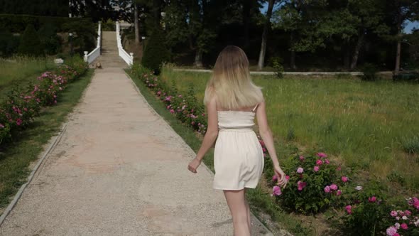 Running Slender Girl with Lush Hair in a Dress in the Park