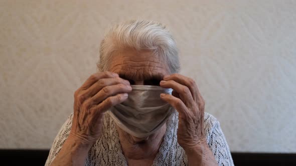 Slow Motion Portrait of an Old Woman Putting on a Protective Medical Mask.
