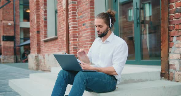 Male Manager in Headset Leading Working Meeting Through Video Call on Laptop alt