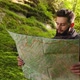 The Guy Is Standing in the Forest and Looking at a Map of the Area