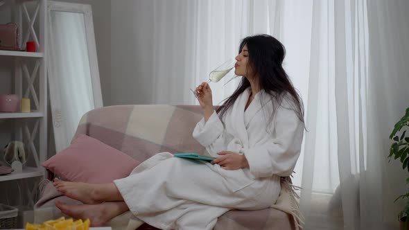 Live Camera Zoom in to Relaxed Happy Middle Eastern Bride Sitting on Couch Drinking Champagne and alt