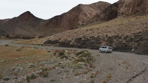 Offroad Vehicle Goes on a Dirt Road Among the Mountains alt