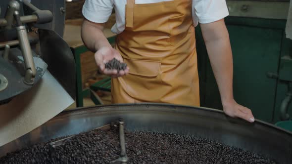 Young man sniffing coffee roasted from the oven in his own factory, starting a family business