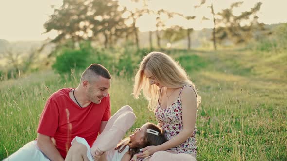 Young mother and father with cute little daughter have a good time together in the woods. alt