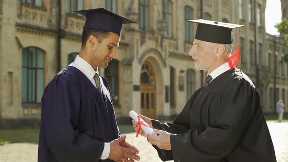 University Chancellor Giving Diploma to Male Student Shaking Hand Graduation Day alt