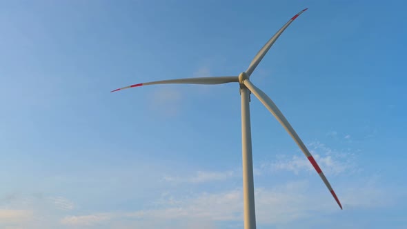 Wind turbine in an offshore wind farm in the green field against low sun on sun