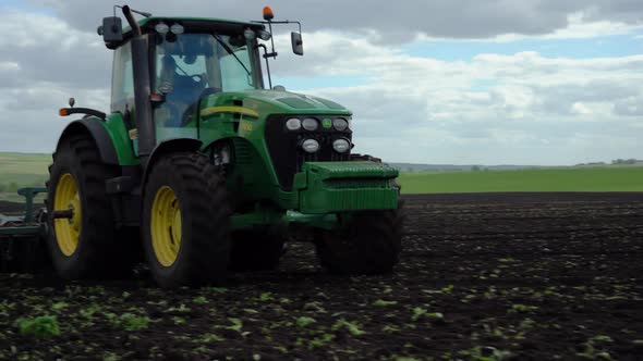 Tractor plows the ground with a plow in the field alt