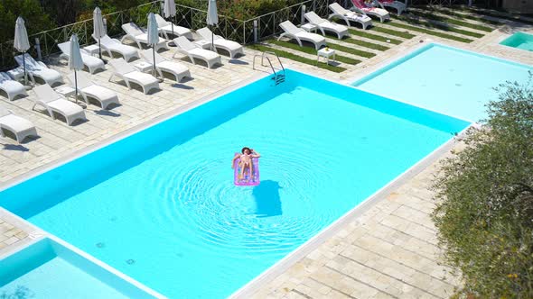 Young Woman in Bikini Air Mattress in the Big Swimming Pool alt
