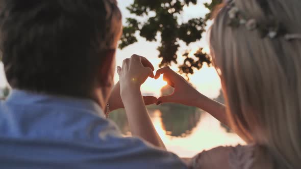 Young Couple Making a Heart Shape From Their Hands alt