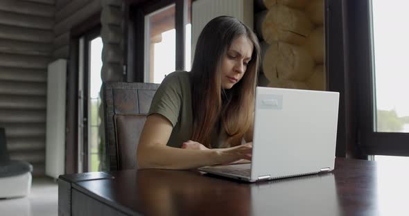 Serious Young Busy Businesswoman Working at a Laptop at Home alt