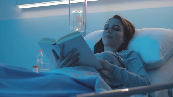 Female patient lying in a hospital bed and reading a book