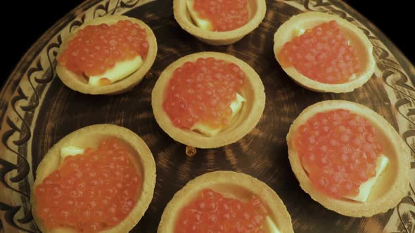 Red Caviar Is Put with a Spoon on Tartlets. Preparation of Snacks with Red Caviar. Top View alt