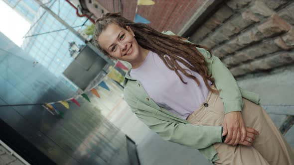 Rotating Portrait of Unique Girl with Dreadlocks Smiling Standing Outside in Modern City alt
