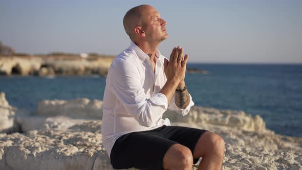 Side View Portrait of Tattooed Caucasian Man Meditating at Picturesque Mediterranean Sea Coast alt