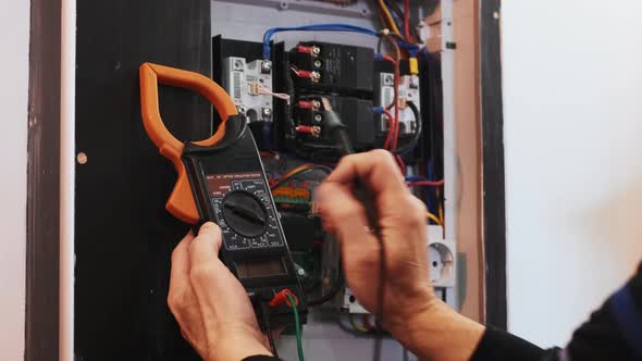 Electricians hands testing current  electric in control panel. alt