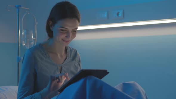 Young patient lying in bed at the hospital and connecting with a tablet