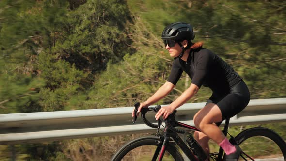 Professional cyclist riding bike through mountain countryside. alt