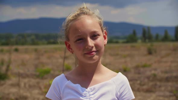 Adorable Smiling Girl Standing on Field at Sunny Summer Day alt