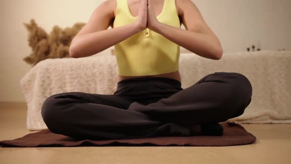 A Woman Without a Face Sits in a Yoga Pose