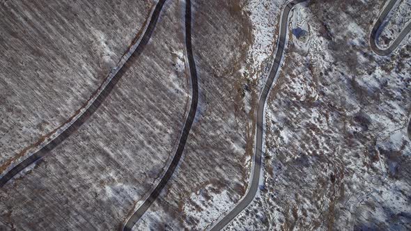 Aerial view of a car road surrounded by snow and trees in Greece. alt