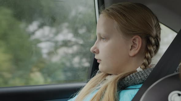 A Girl of Ten Years Old Rides in the Back Seat of a Car alt