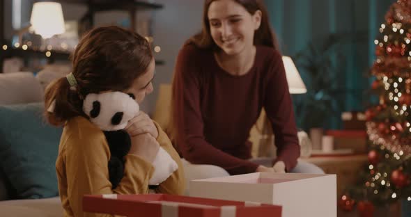 Girl receiving a cute Christmas gift from her sister, family and holidays concept