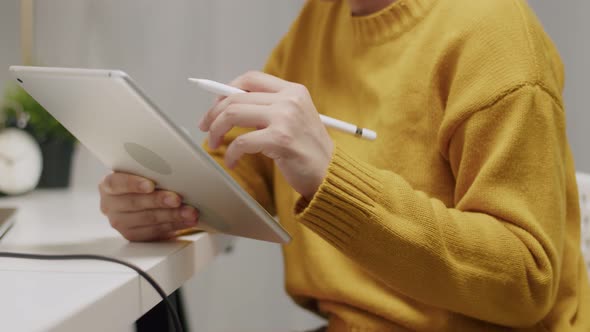 Asian woman using a tablet write an article and searching on the internet. alt