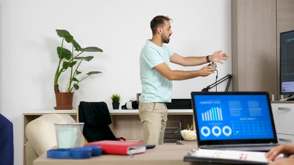 Man Playing a Video Game on the Console While Her Partner Is Working on the Computer alt
