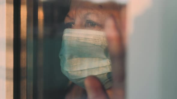 Elderly Woman at Window in Protecting Medical Mask on Selfisolation alt