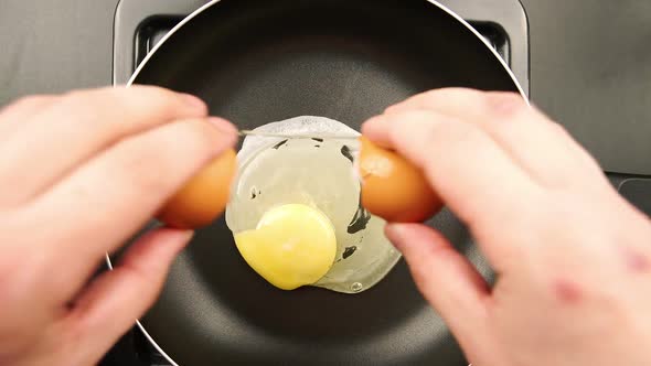 Human hands putting egg on the frying pan