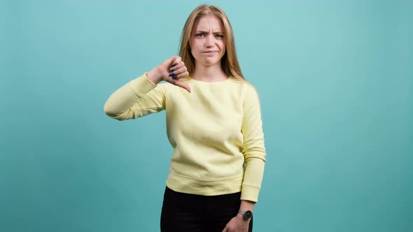 Young Girl Making a Thumbs Down Gesture Expressing Discontent Disapproval alt