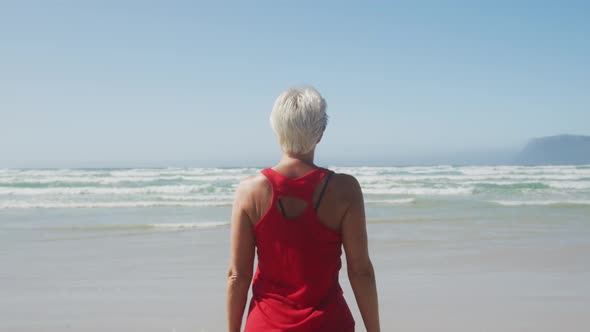 Senior woman stretching in the beach alt