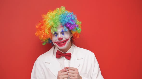 A Clown Smiling with a Happy Face Dressed in a White Outfit and a Bow Tie with a Painted Face on an alt