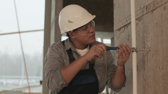 Woman Screwing on Pipe to Wall alt