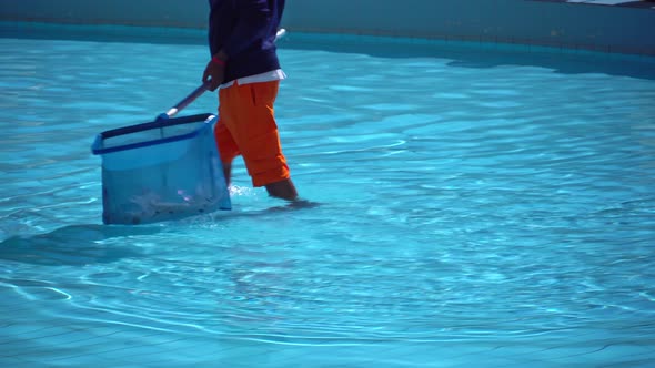 A Man Removes Garbage From the Pool with a Sap alt